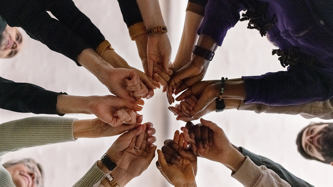 Work colleagues join hands in the centre of a circle.